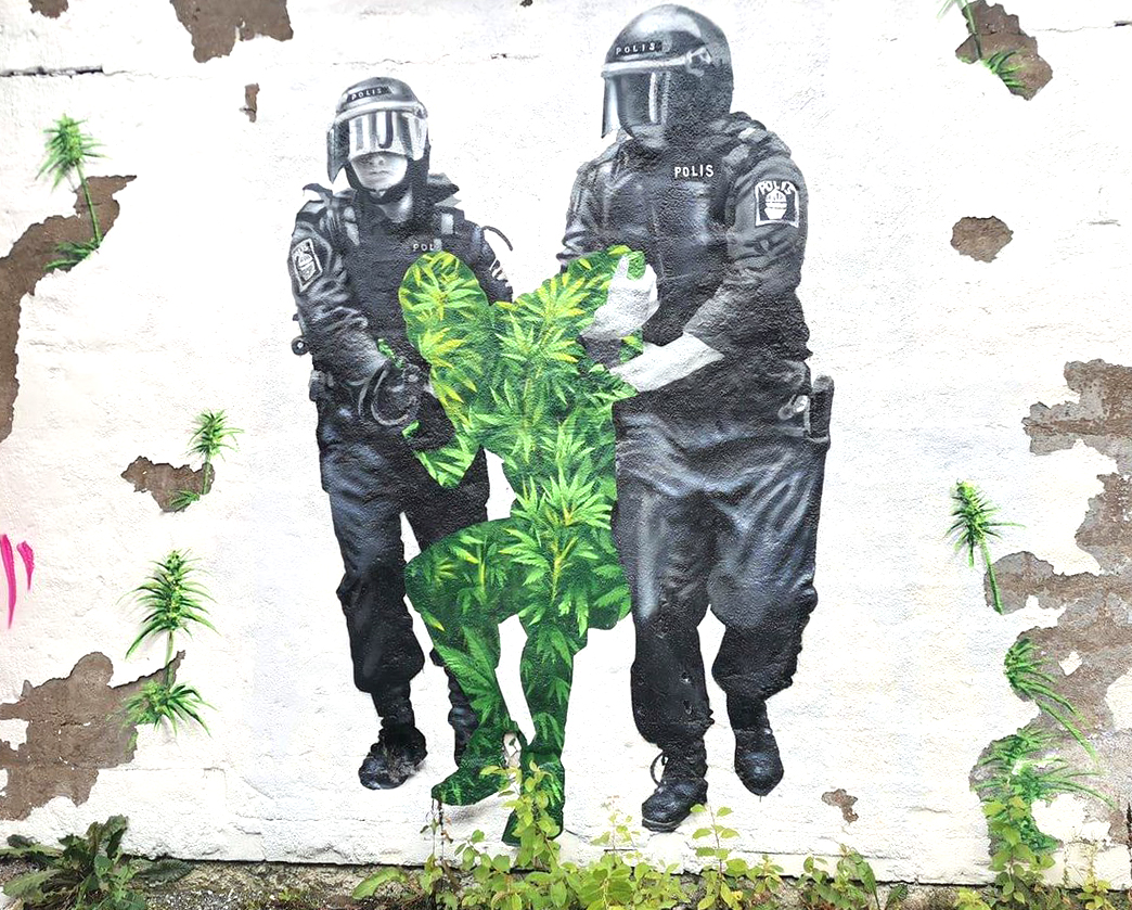 Photographed graffiti wall painting of police detaining a person associated with Cannabis.